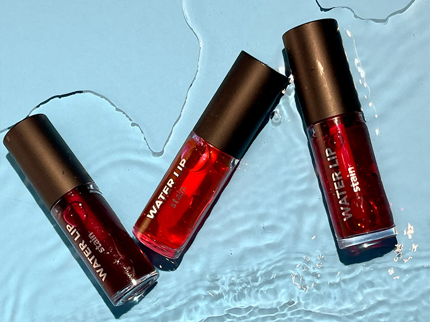 Flormar Water Lip Stain collection in vibrant red shades, displayed on a refreshing water-textured background.